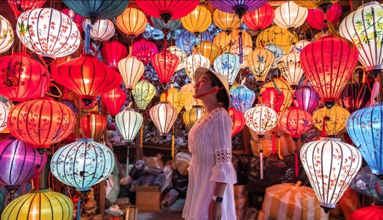a person standing in front of a wall of colorful lanterns