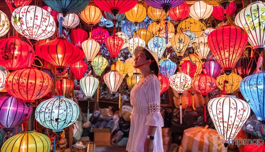 a person standing in front of a wall of colorful lanterns