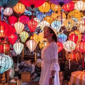 a person standing in front of a wall of colorful lanterns